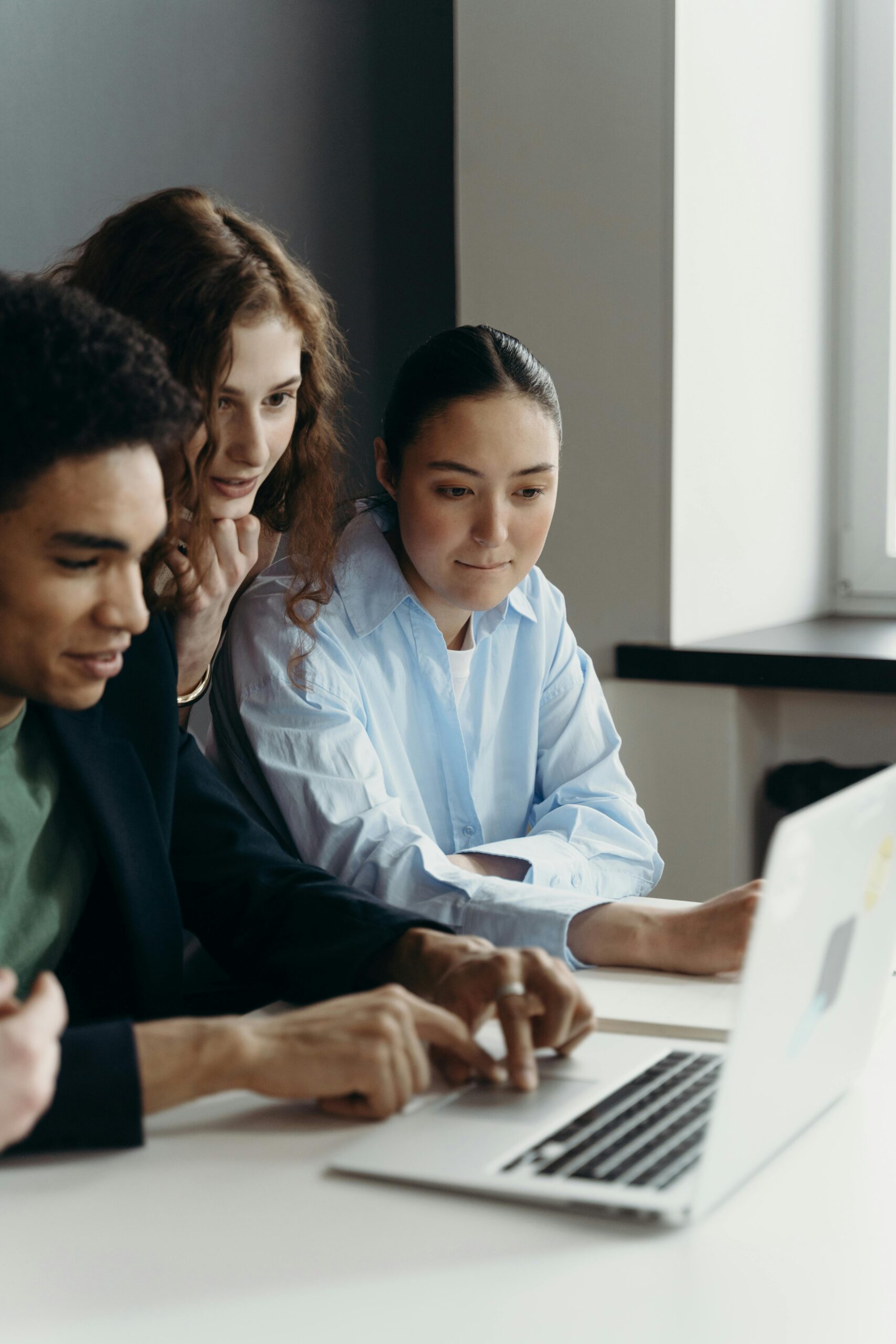 A diverse team of professionals collaborating on a laptop in an office setting.